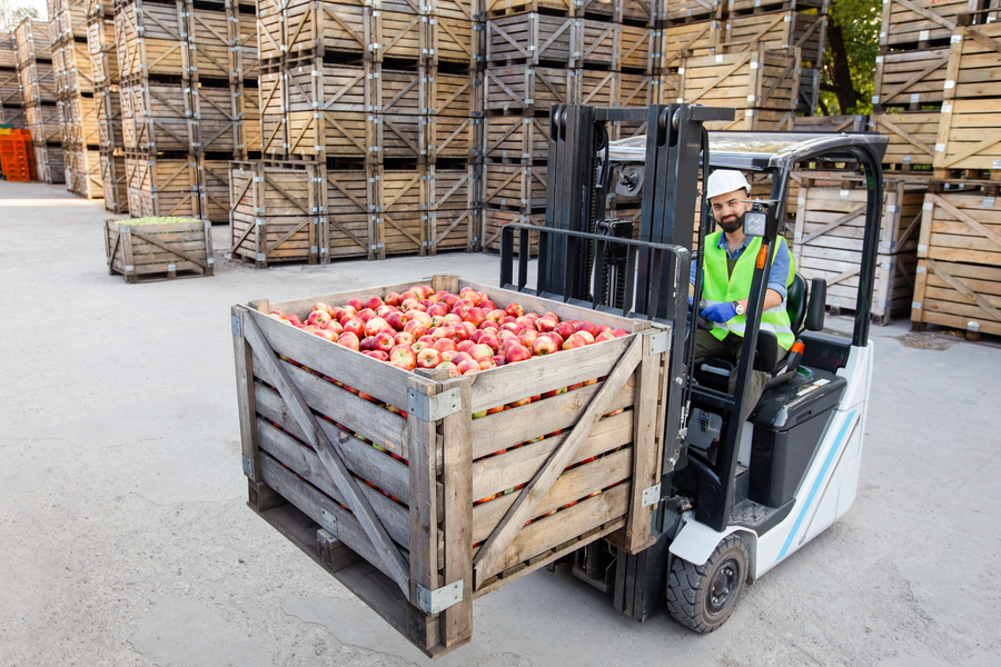 A forklift with a pallet of apples loaded in a factory
